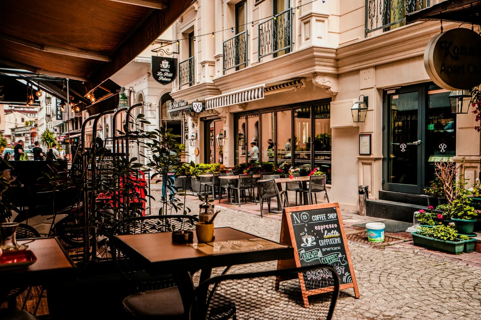 Sidewalk cafe tables beside a chalkboard menu on a cobbled street