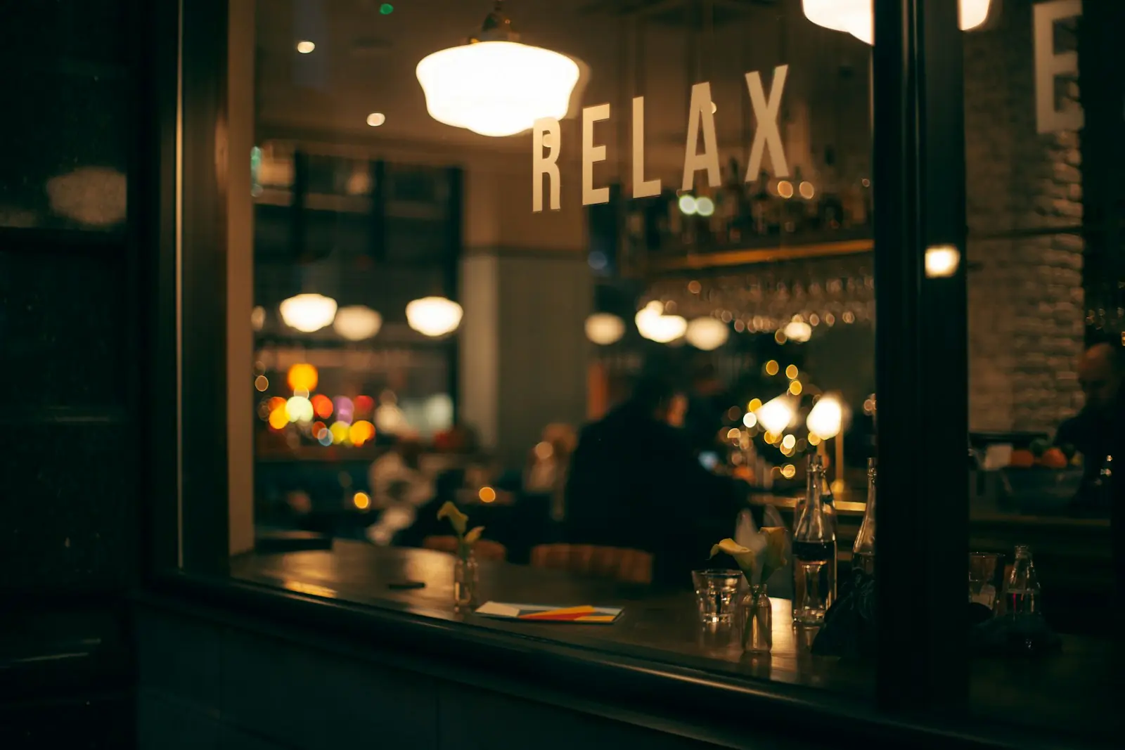 Interior de un bar de noche visto a través de la ventana, con la palabra RELAX en el vidrio